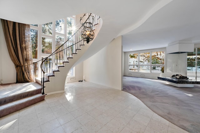 entryway featuring a chandelier, light colored carpet, plenty of natural light, and stairs