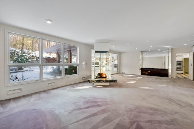 unfurnished living room with recessed lighting, baseboards, and light colored carpet