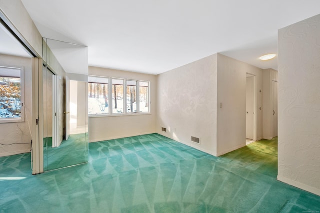 unfurnished room featuring a textured wall, carpet, and visible vents