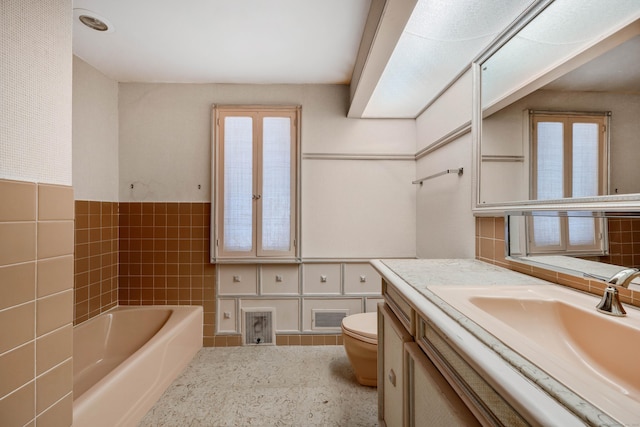 full bath with toilet, a bathing tub, visible vents, vanity, and tile walls