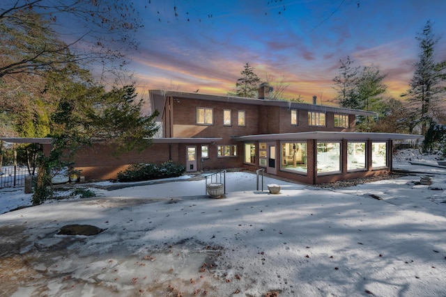 snow covered property with brick siding