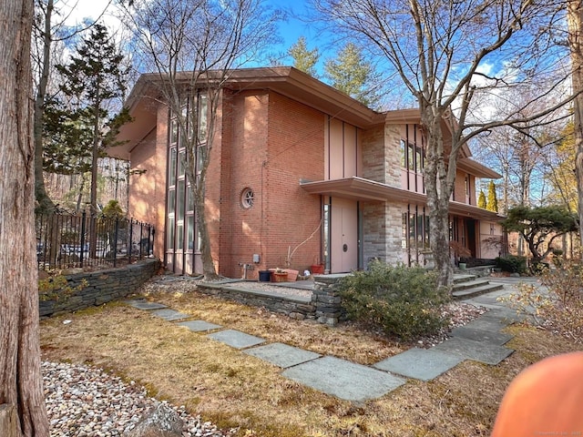 exterior space featuring stone siding, fence, and brick siding