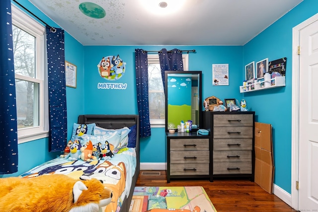 bedroom featuring multiple windows and dark hardwood / wood-style flooring