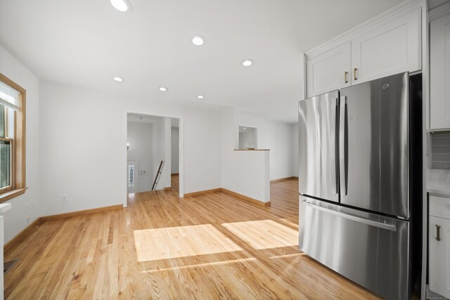 kitchen featuring stainless steel fridge, light wood-type flooring, and white cabinets