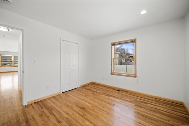 unfurnished bedroom featuring a closet, wood-type flooring, and multiple windows