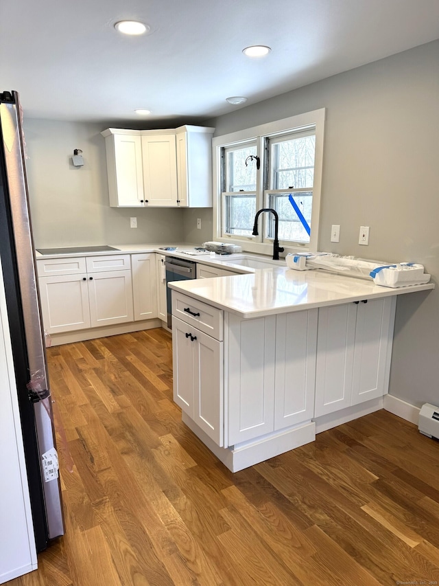 kitchen featuring white cabinetry, appliances with stainless steel finishes, light wood-type flooring, and kitchen peninsula