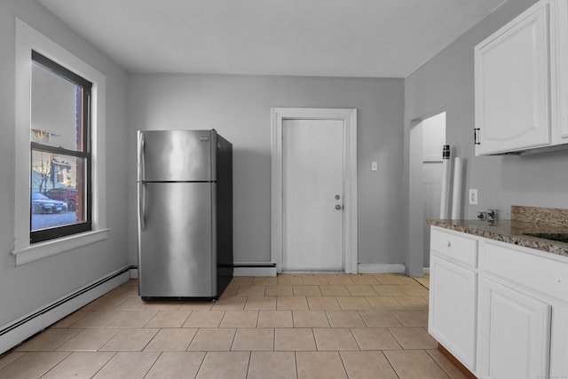 kitchen featuring stone countertops, stainless steel refrigerator, white cabinetry, a baseboard radiator, and sink