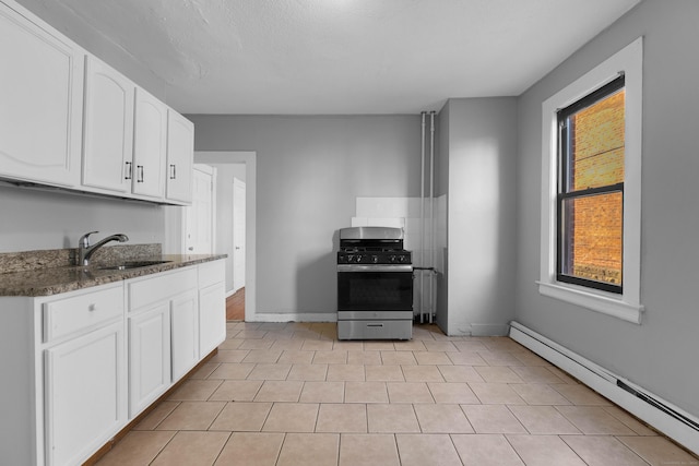 kitchen with sink, stainless steel range with gas stovetop, white cabinets, a baseboard radiator, and dark stone counters