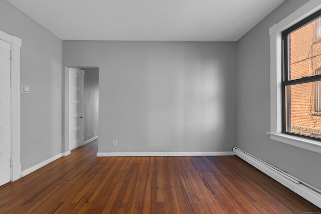 empty room featuring dark wood-type flooring and baseboard heating