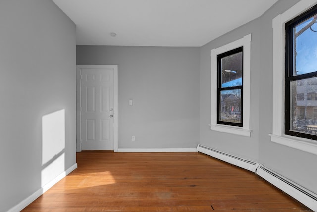 spare room with a baseboard heating unit, light hardwood / wood-style flooring, and a healthy amount of sunlight