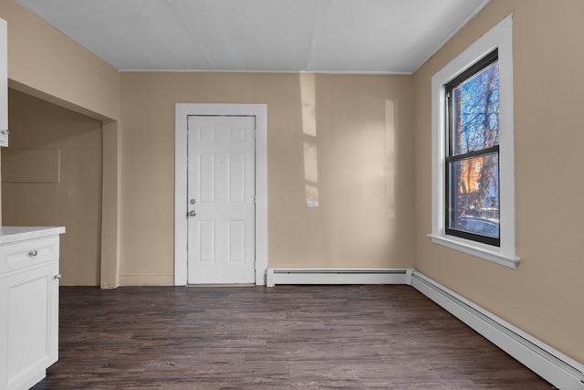 interior space with a wealth of natural light, dark hardwood / wood-style floors, and baseboard heating