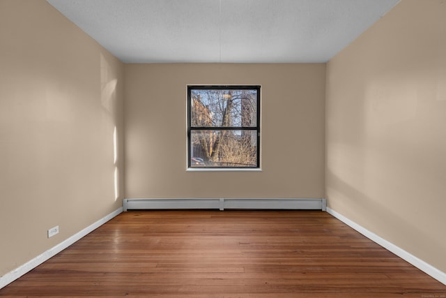 empty room with hardwood / wood-style flooring and baseboard heating