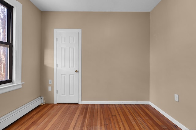 spare room with a healthy amount of sunlight, baseboard heating, and light wood-type flooring