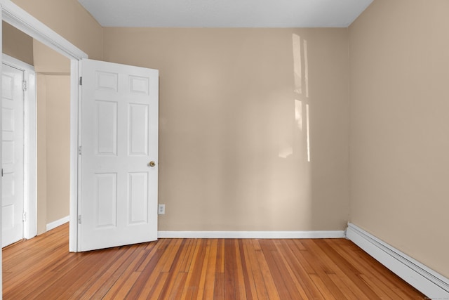 spare room with a baseboard heating unit and wood-type flooring