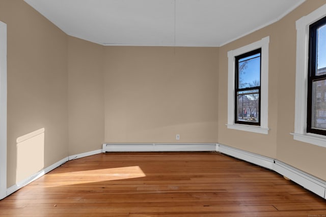 unfurnished room featuring a baseboard heating unit, crown molding, and light hardwood / wood-style flooring