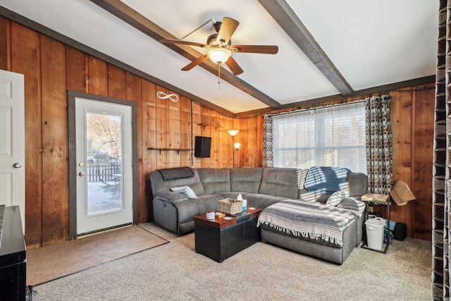 carpeted living room with vaulted ceiling with beams, ceiling fan, and wood walls