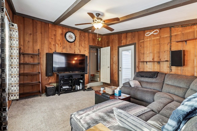 carpeted living room with beamed ceiling, ceiling fan, and wooden walls