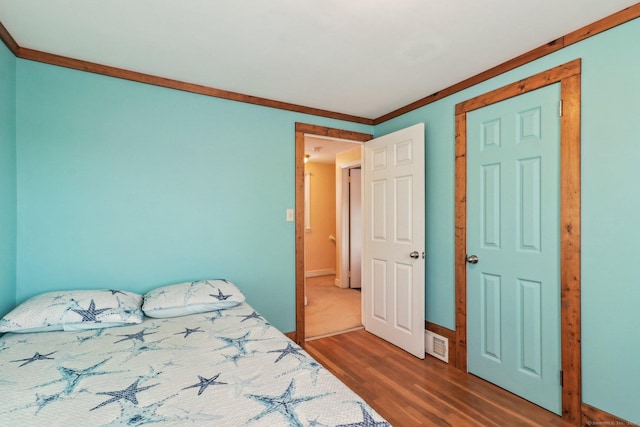 bedroom with crown molding and dark wood-type flooring