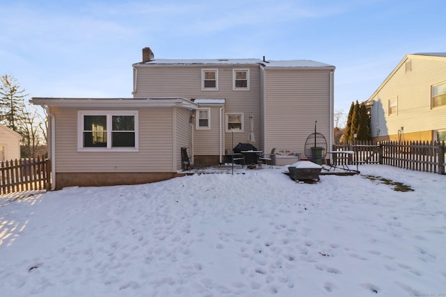 snow covered rear of property with a fire pit