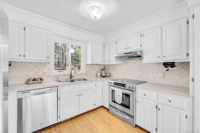 kitchen with appliances with stainless steel finishes, sink, white cabinets, and light hardwood / wood-style flooring