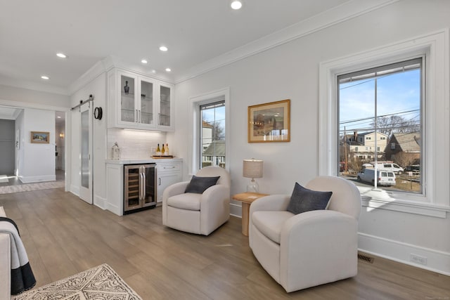 living room with wine cooler, plenty of natural light, ornamental molding, and a barn door