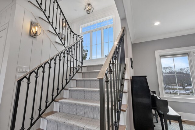 stairway featuring ornamental molding and a healthy amount of sunlight