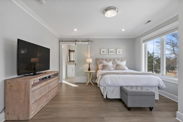 bedroom featuring hardwood / wood-style floors, crown molding, and a barn door