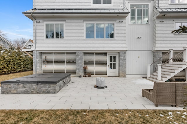 rear view of house featuring a hot tub and a patio area