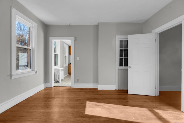 unfurnished bedroom featuring radiator heating unit and light hardwood / wood-style floors