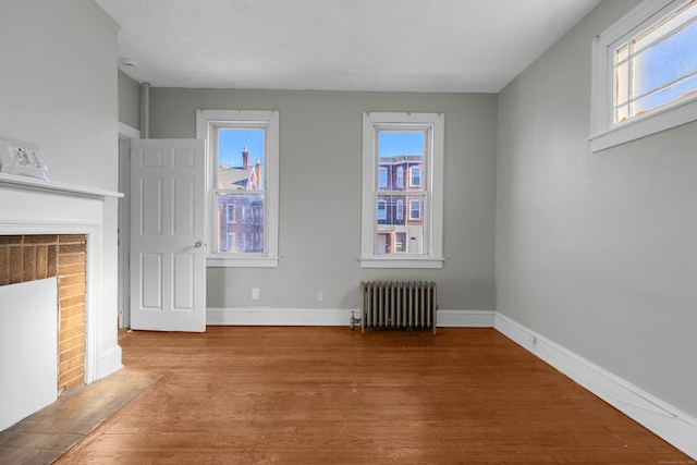 unfurnished living room featuring radiator, a fireplace, and light hardwood / wood-style floors