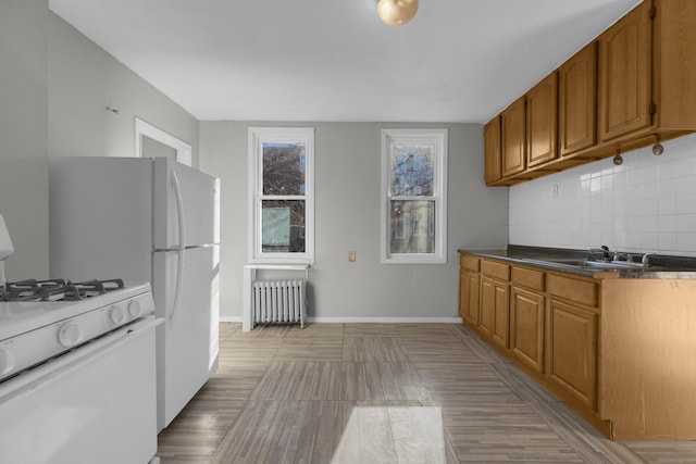 kitchen featuring tasteful backsplash, radiator, sink, and gas range gas stove