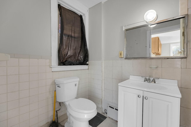 bathroom featuring a baseboard radiator, vanity, toilet, and tile walls