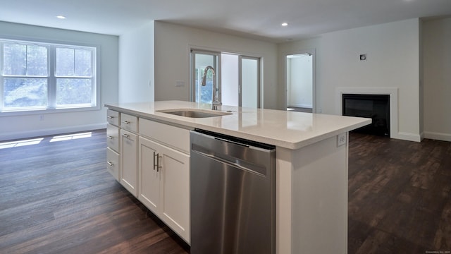 kitchen with baseboards, dishwasher, a glass covered fireplace, dark wood-style floors, and a sink