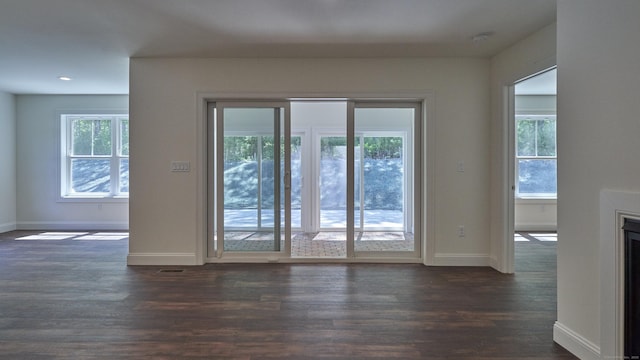 doorway to outside with plenty of natural light, dark wood-type flooring, a fireplace, and baseboards