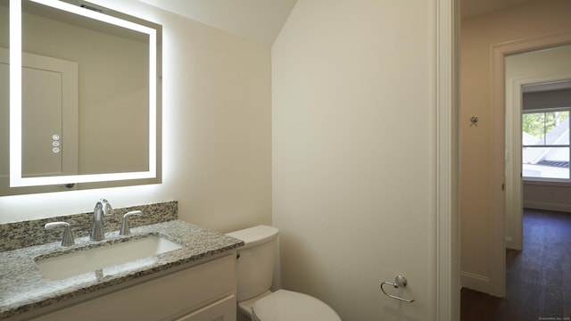 bathroom with wood finished floors, vanity, toilet, and baseboards