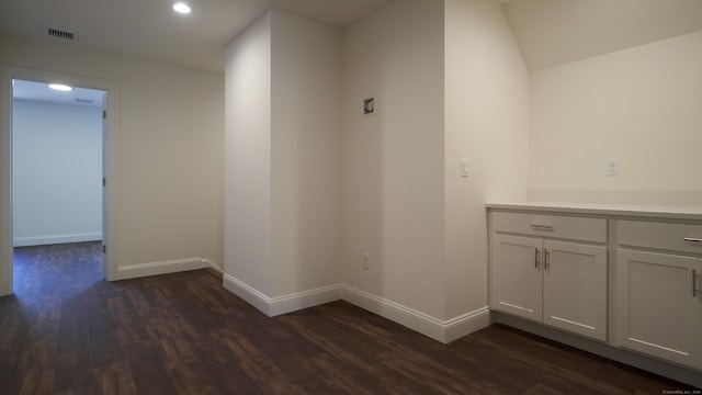 hallway with dark wood-style floors, baseboards, visible vents, and recessed lighting