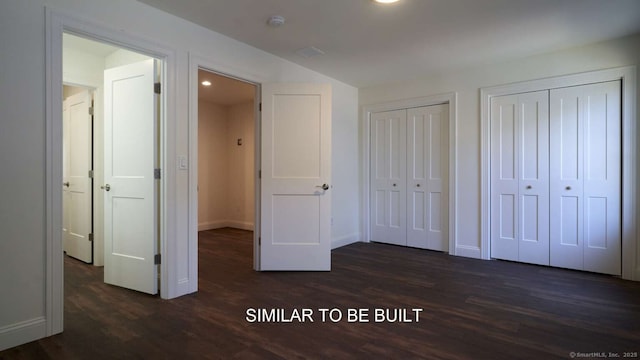 unfurnished bedroom with dark wood-type flooring and multiple closets