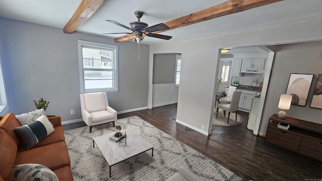 living room featuring dark hardwood / wood-style flooring, sink, beam ceiling, and ceiling fan