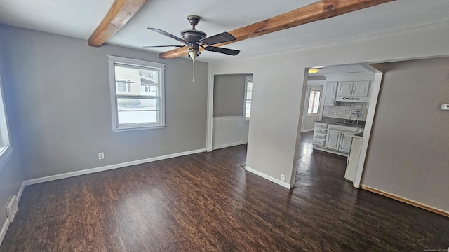 unfurnished living room with dark wood-type flooring, ceiling fan, beam ceiling, and sink