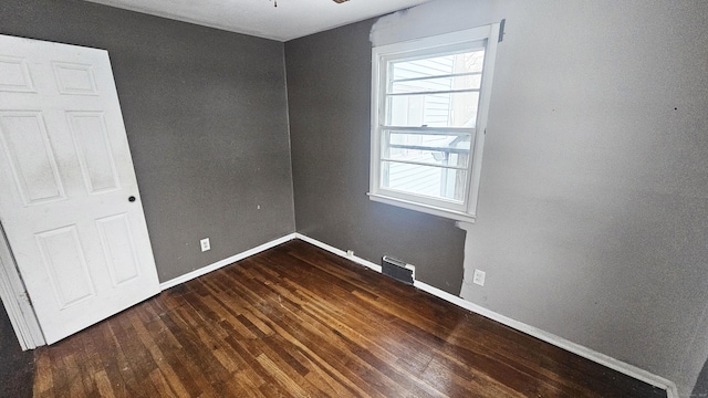 spare room featuring plenty of natural light and dark hardwood / wood-style flooring