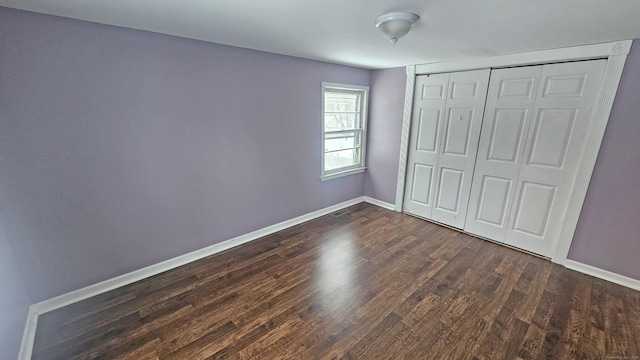 unfurnished bedroom with dark wood-type flooring and a closet