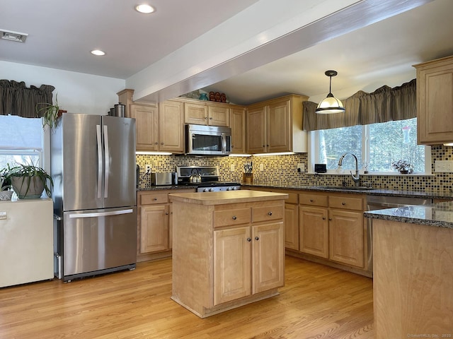 kitchen with sink, a kitchen island, stainless steel appliances, and light wood-type flooring