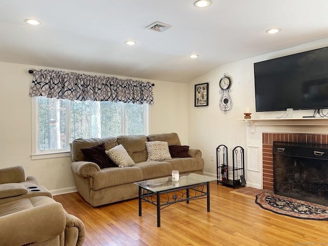 living room with lofted ceiling, a fireplace, and hardwood / wood-style floors