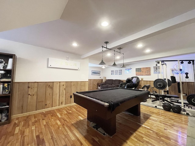 recreation room with billiards, wooden walls, a wall unit AC, and light hardwood / wood-style flooring