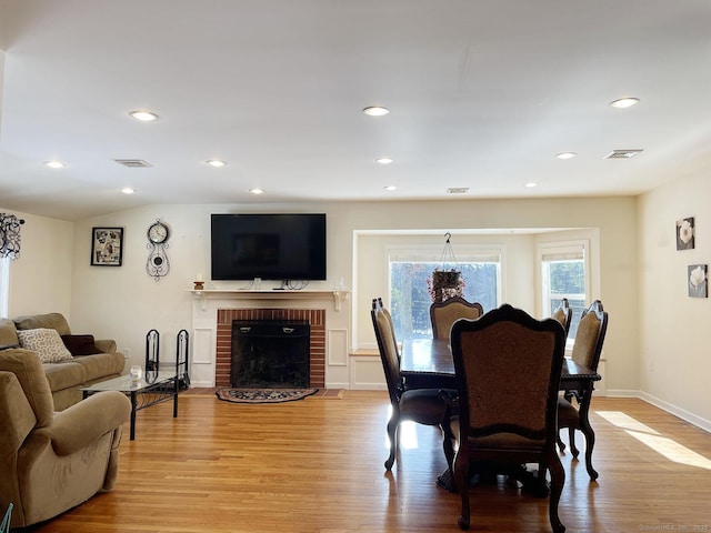 dining room featuring vaulted ceiling, a fireplace, and light hardwood / wood-style floors