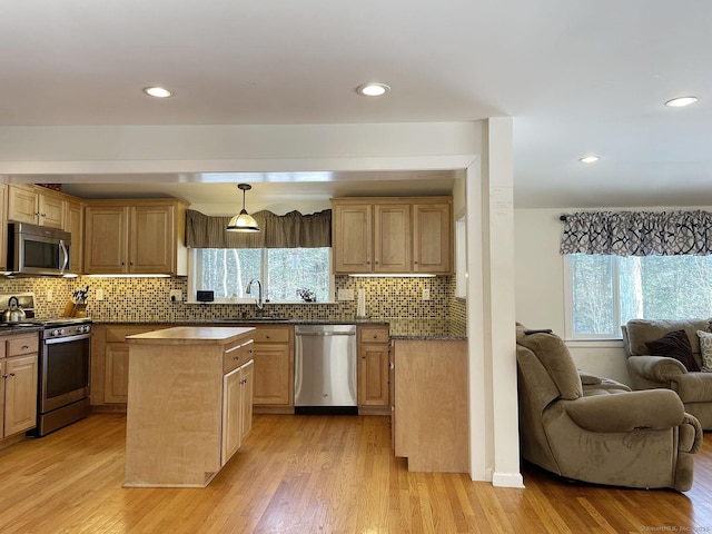 kitchen featuring decorative backsplash, a wealth of natural light, stainless steel appliances, and light wood-type flooring