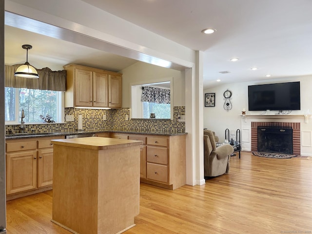 kitchen with tasteful backsplash, light brown cabinets, light hardwood / wood-style floors, and a kitchen island