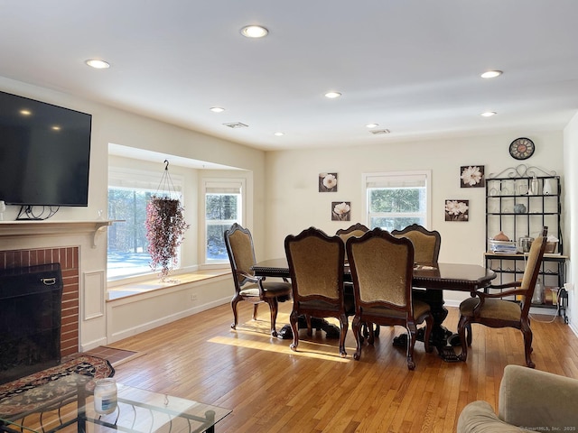 dining space with a fireplace, plenty of natural light, and light hardwood / wood-style floors