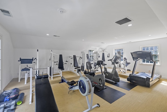 workout area with lofted ceiling and light carpet