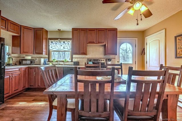 kitchen with hanging light fixtures, backsplash, a wealth of natural light, and light wood-type flooring